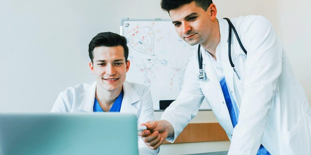 dupla de médicos ao computador lendo sobre SEO e marketing digital para médicos