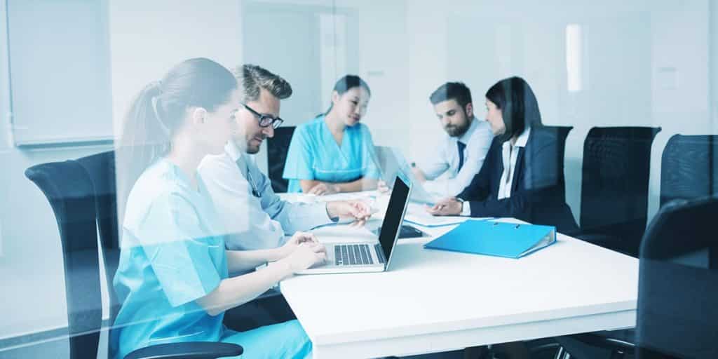 equipe em hospital reunida em mesa debatendo marketing em gestão hospitalar