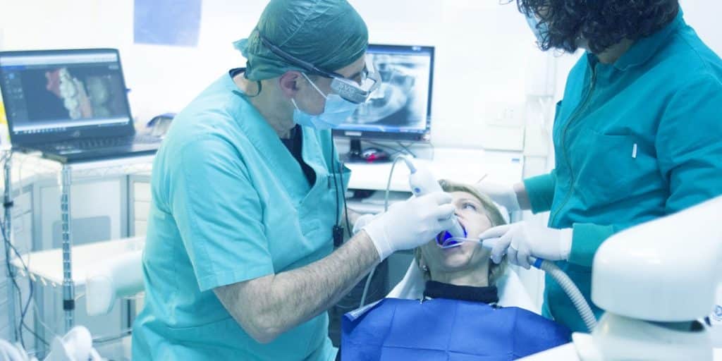 dentista e assistente tratando paciente que chegou pelas boas postagens para instagram odontologia