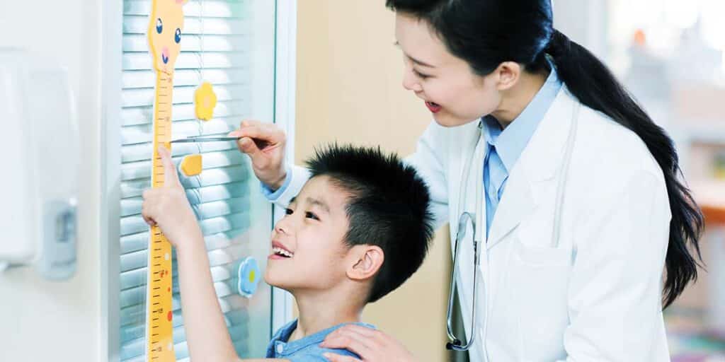 Pediatra medindo a altura de um paciente - site E-clínica agência marketing digital